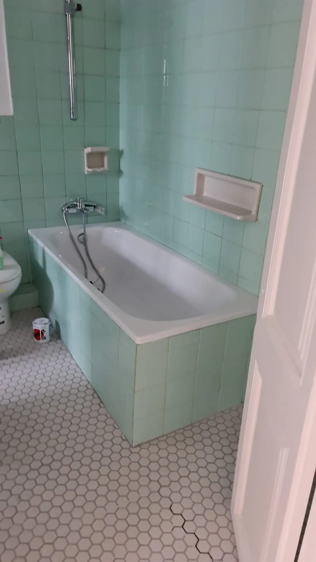 Baño antiguo con bañera y azulejo verde antes de la reforma