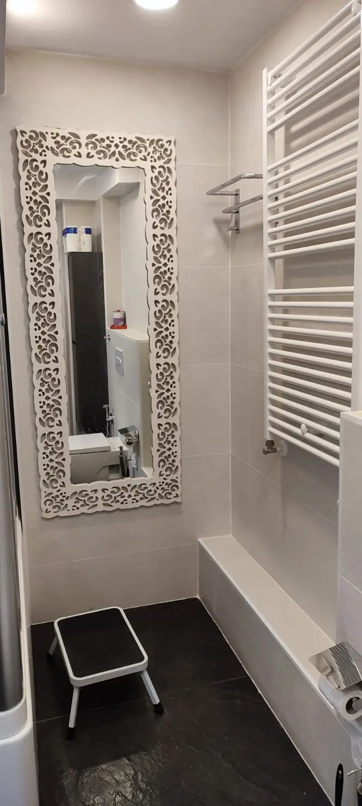 Baño con espejo decorativo, radiador toallero y suelo de pizarra