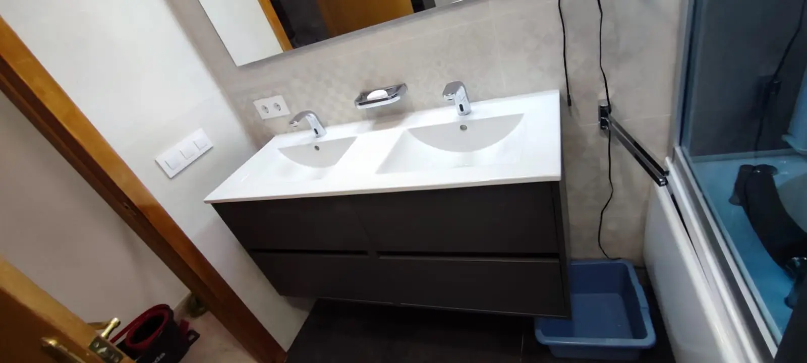 Lavabo doble con grifos electrónicos y mueble suspendido gris