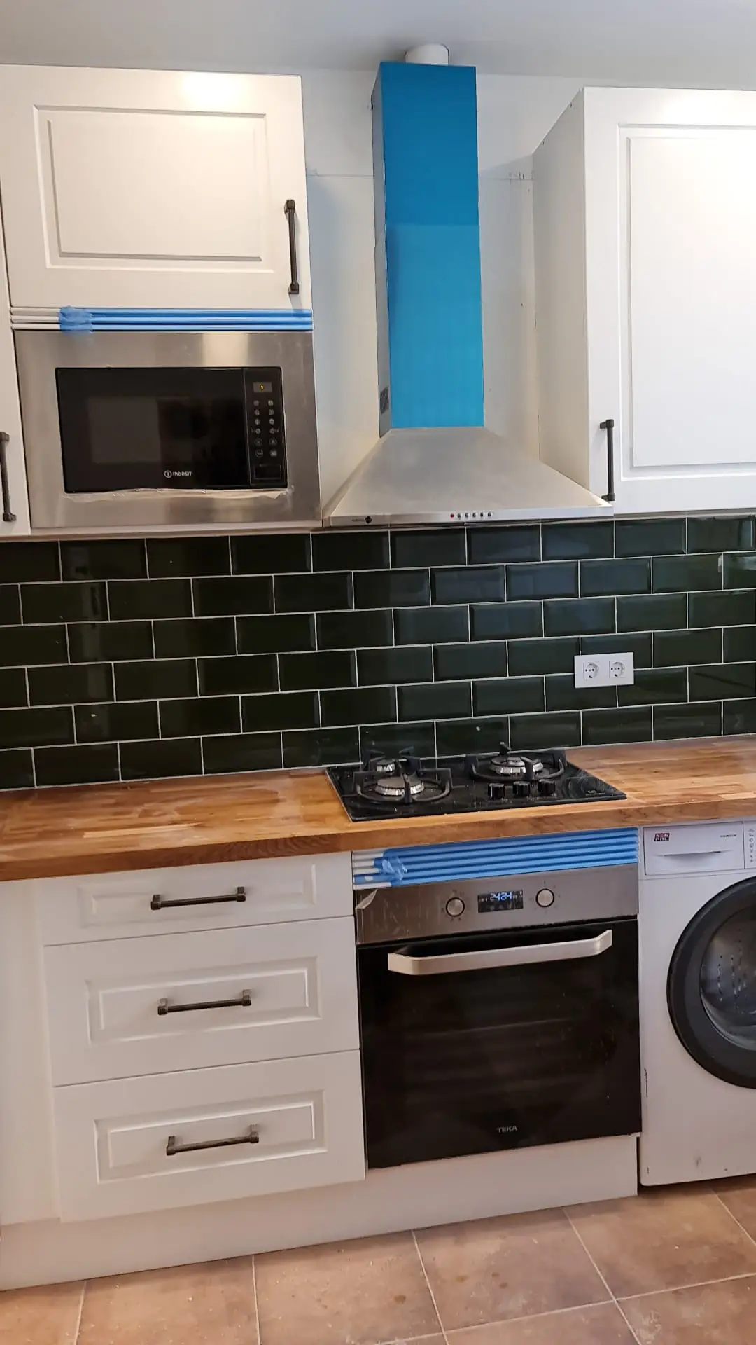 Montaje de cocina con campana extractora, microondas integrado y azulejo verde