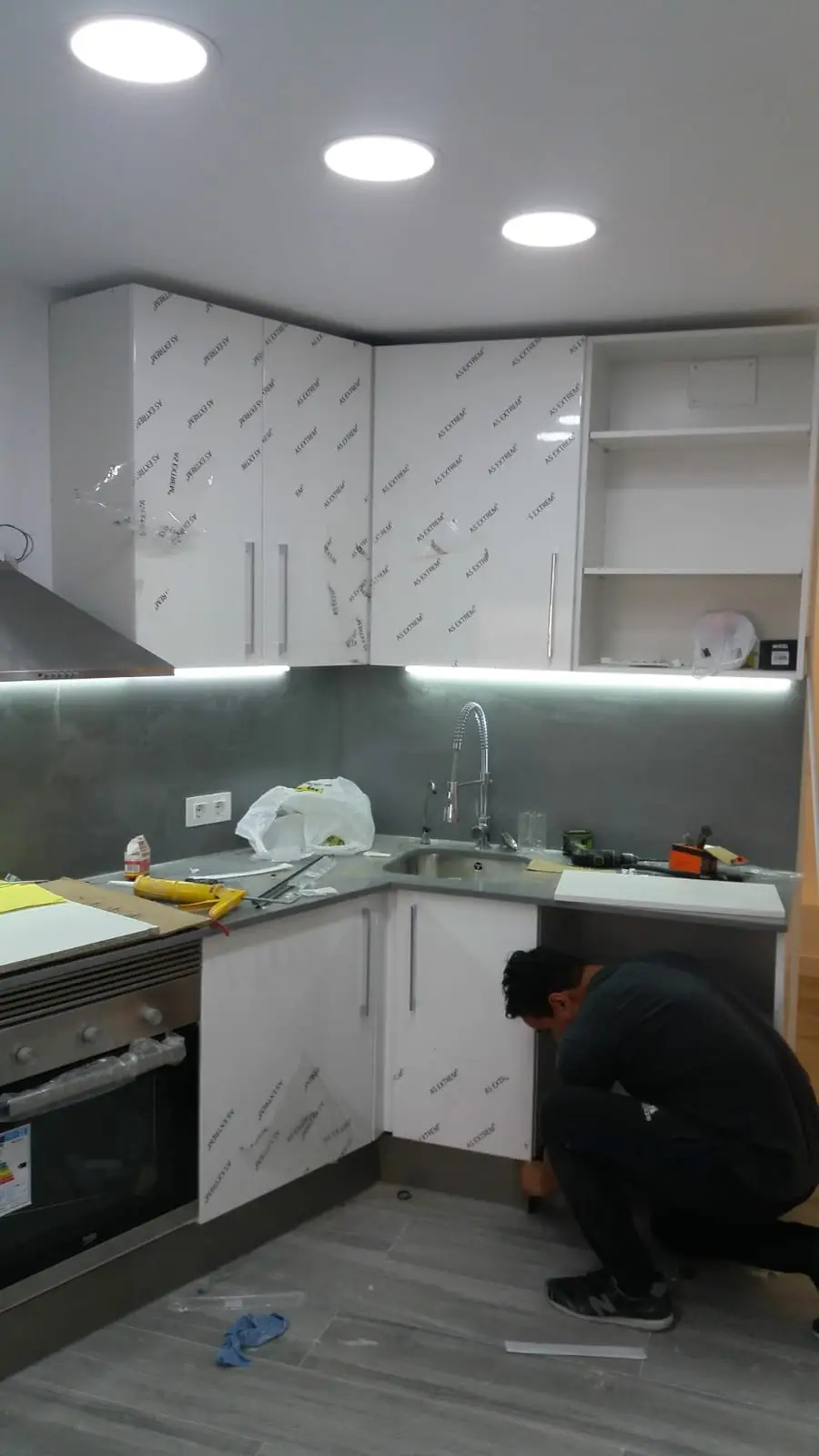 Instalación de cocina blanca brillo con iluminación LED bajo los muebles altos
