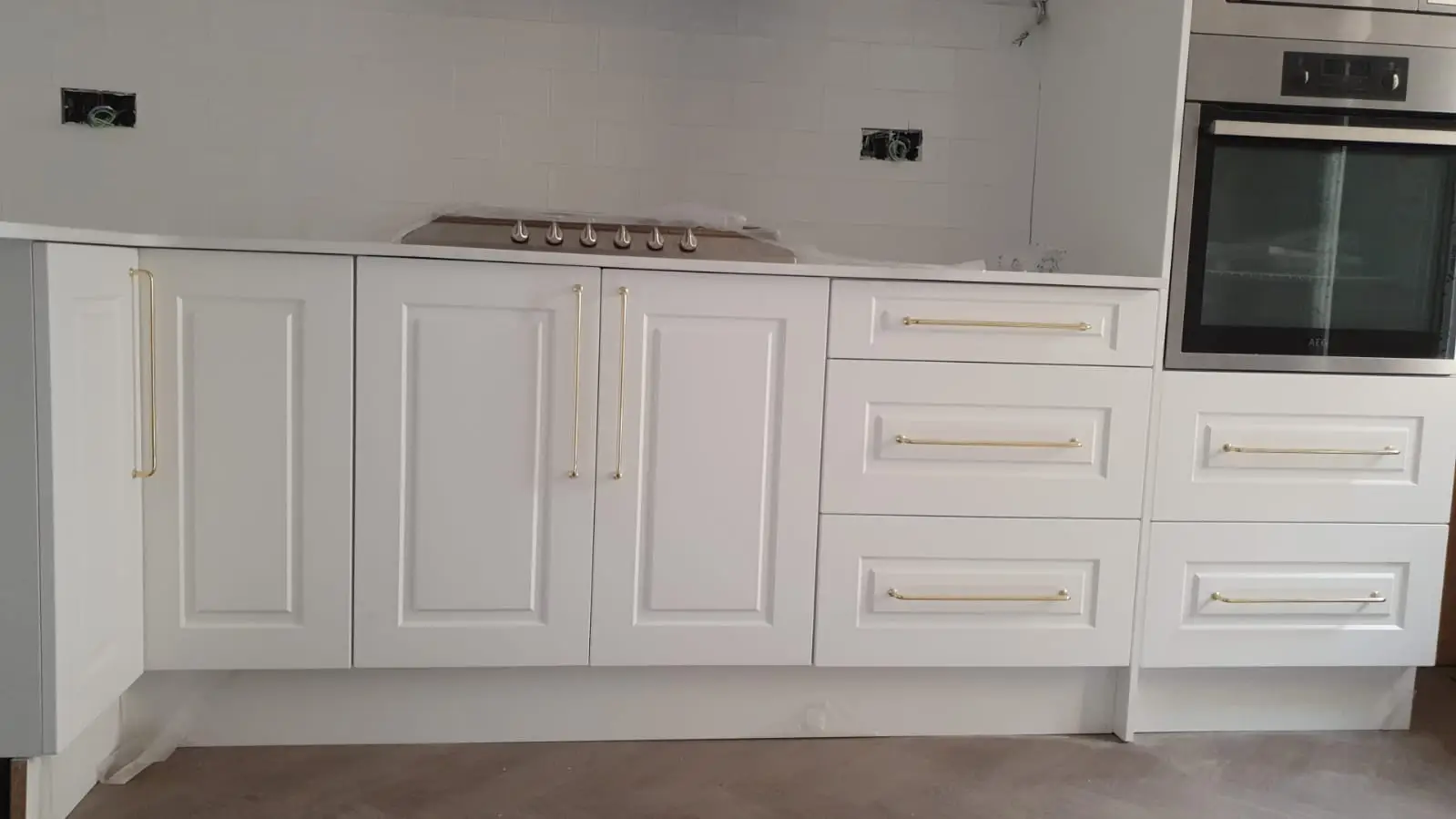 Muebles de cocina blancos de estilo clásico con tiradores dorados y horno en columna