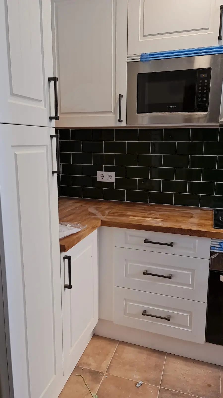 Rincón de cocina con muebles blancos, cajoneras y encimera de madera