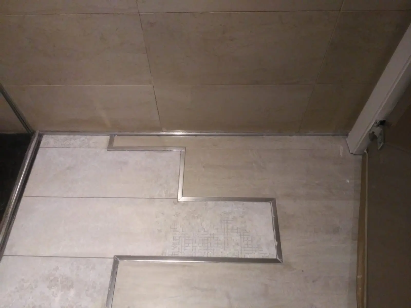 Plato de ducha de obra en porcelánico con juntas de perfil de acero