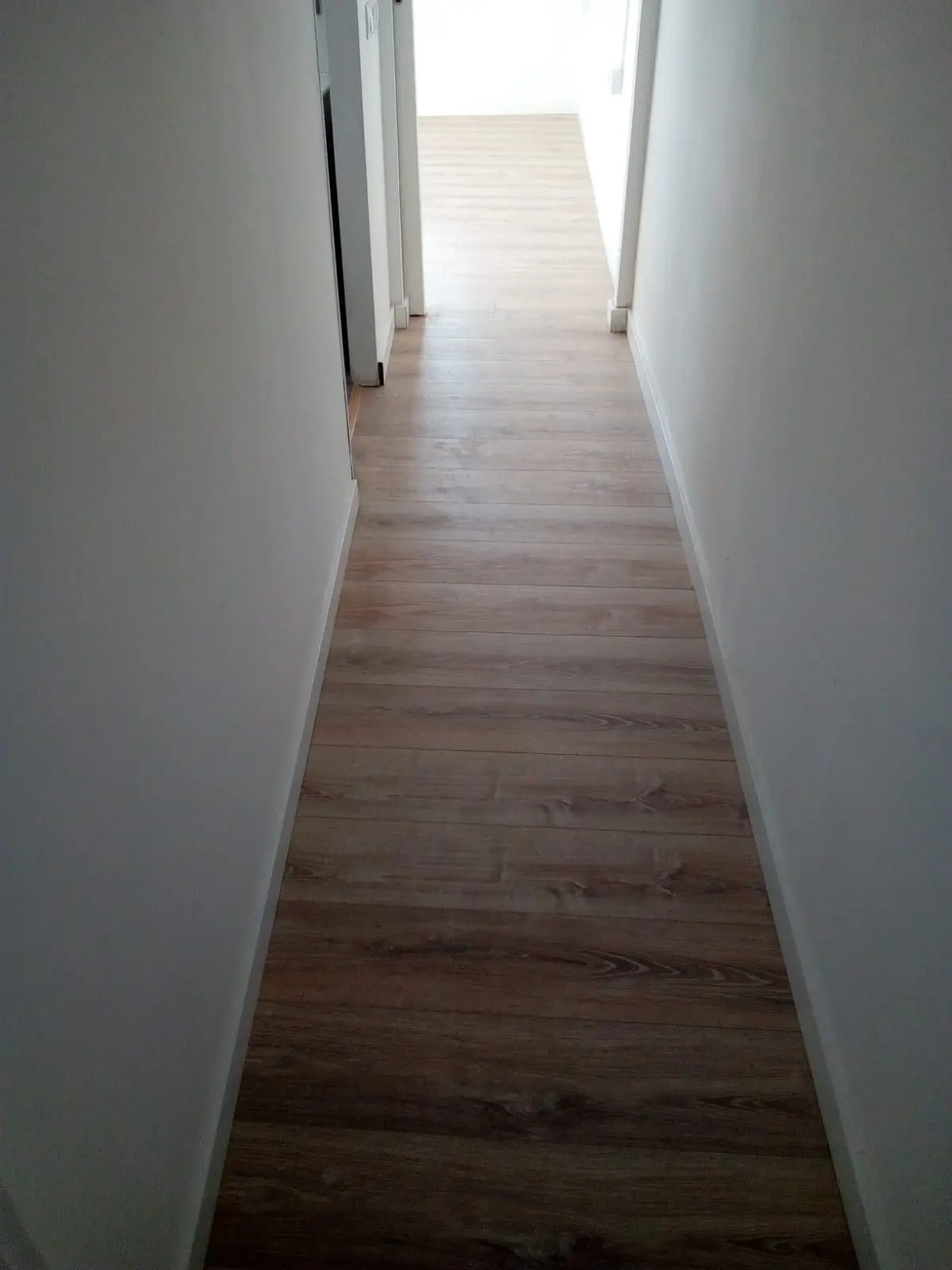 Pasillo estrecho con suelo laminado de madera oscura
