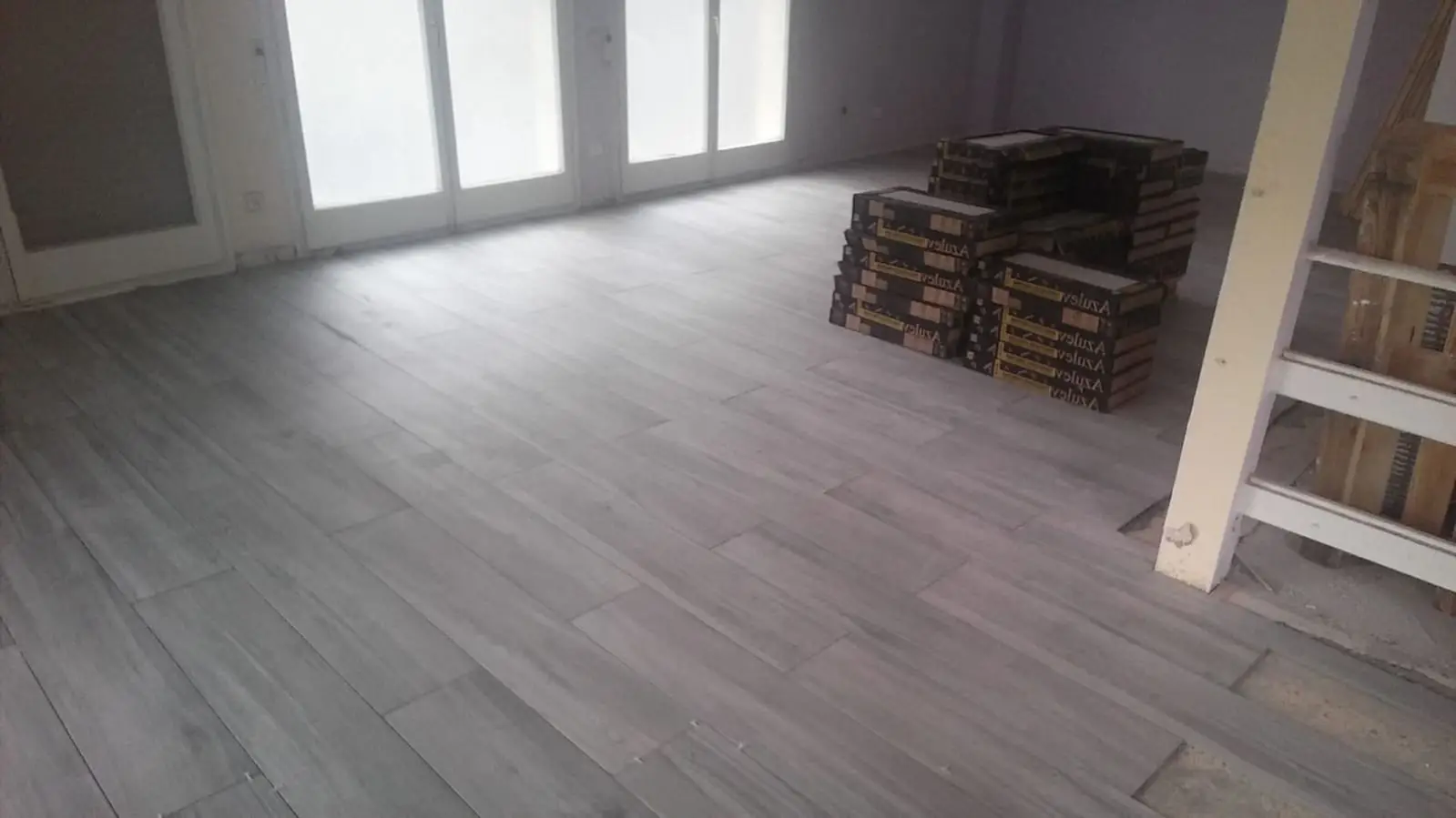 Colocación de suelo porcelánico imitación madera gris en un salón